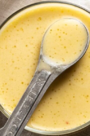 Un tazón lleno de aderezo de limón y ajo con un tenedor y un cuchillo en la parte superior